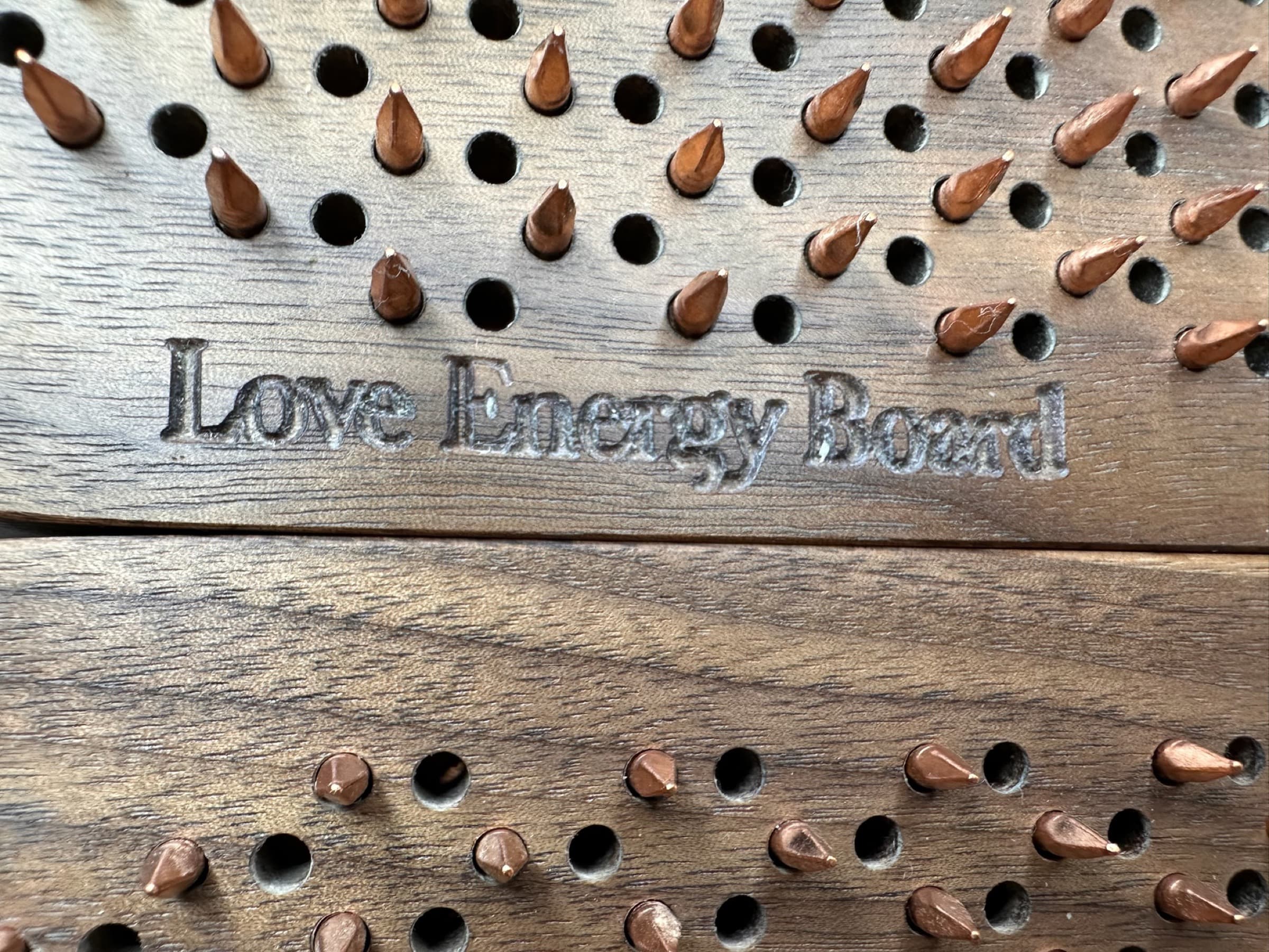 Overhead detail of a Love Energy Board: roughly 800 copper nails hand-set on a 10mm grid into quarter-sawn American walnut.